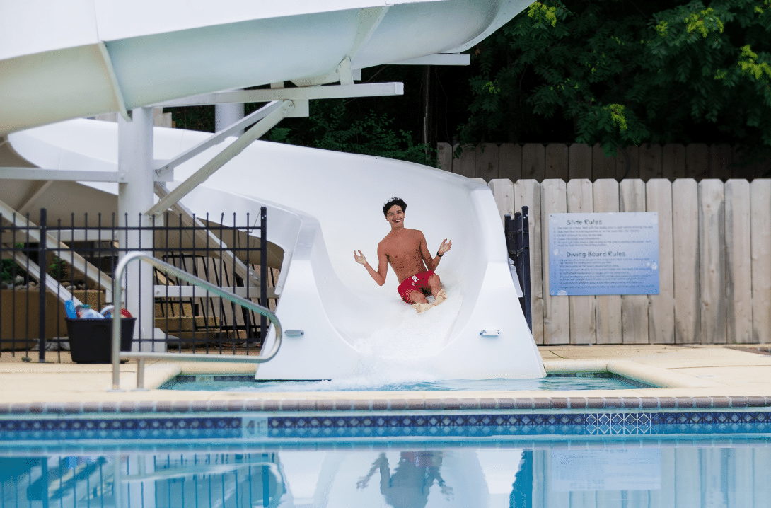 Young male sliding down waterslide into Salina Country Club swimming pool