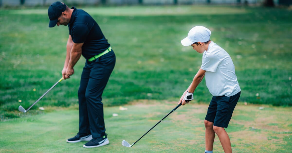 A instructor teaching a kid golf in a junior golf program