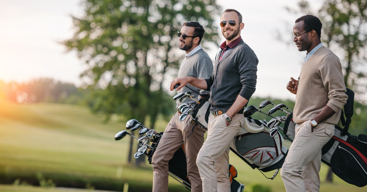 Three men walking through a country club golf course with their golf clubs