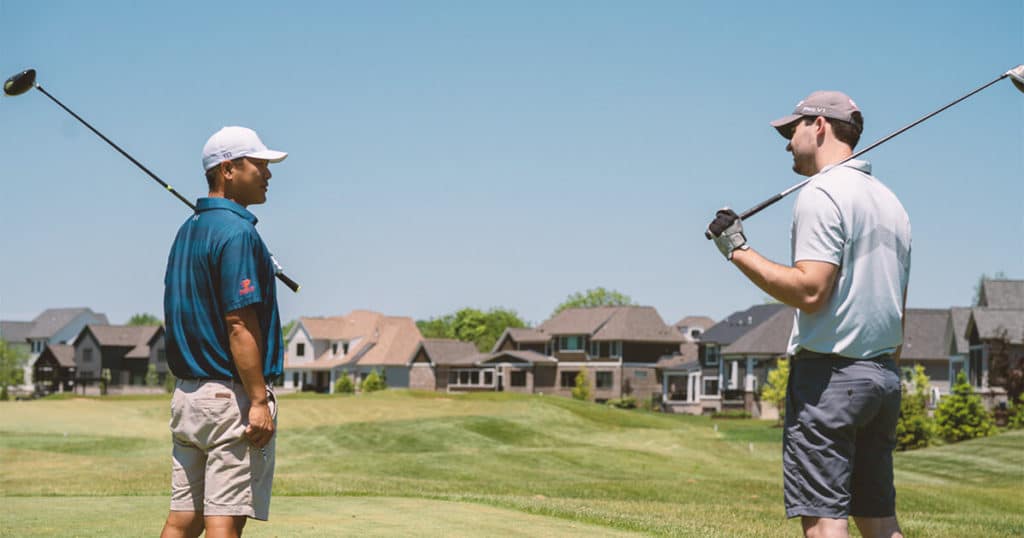 A golfer is giving golf lessons to another person on the greenway