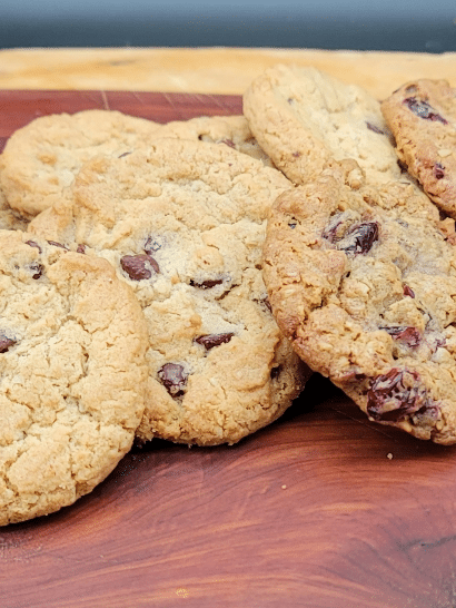 pile of oatmeal craisin cookies on a cherry wood cutting board